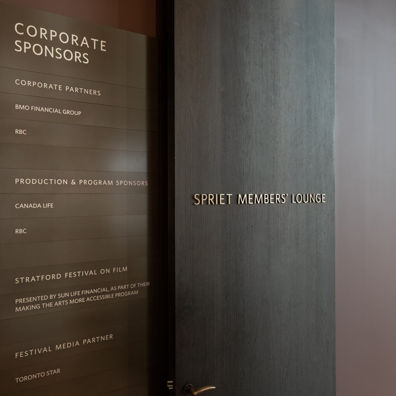 Members lounge identification signage in bronze dimensional letters adjacent to a Corporate Sponsors plaque.