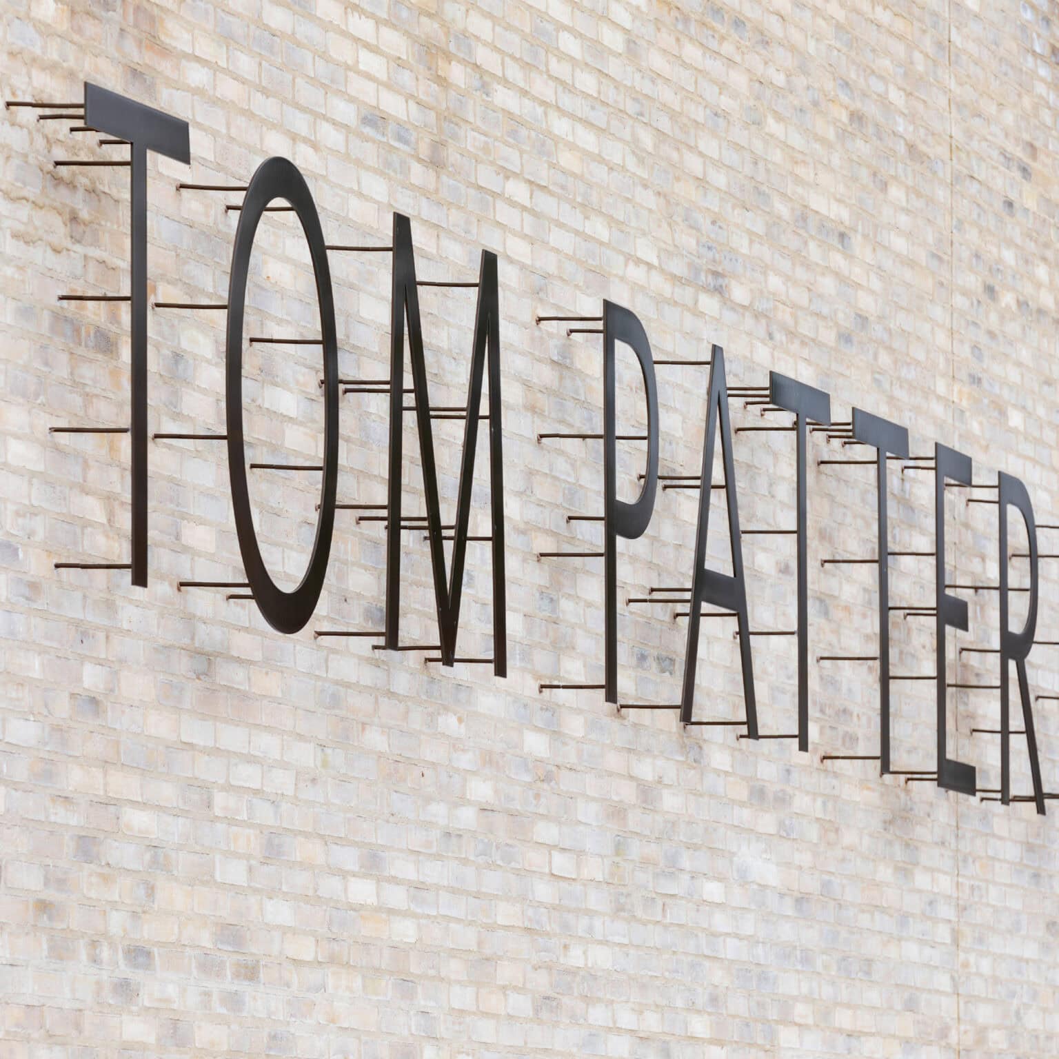 Tom Patterson Theatre sign on back of building mounted on pegs to allow vines to grow.