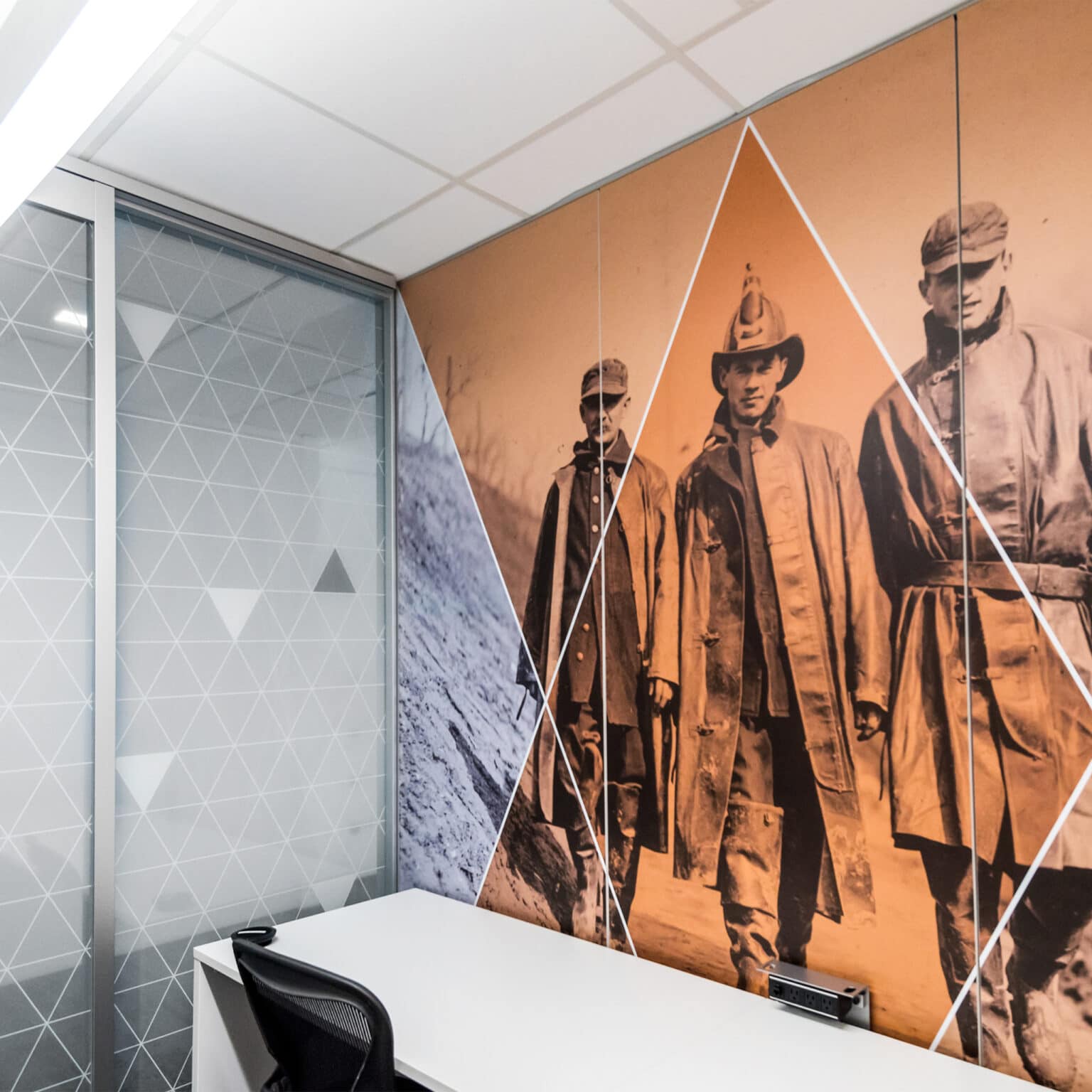 Deloitte workstation featuring a graphic depicting historical firefighters overlaid with an orange screen and subtle diamond pattern.