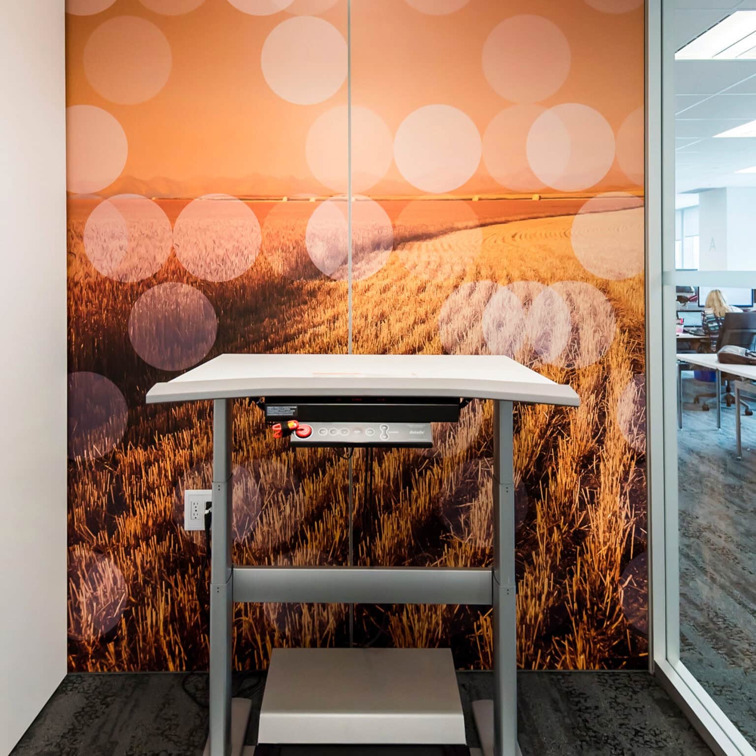 Deloitte workstation graphic featuring a wheat field overlaid by an orange screen of floating circles/suns.