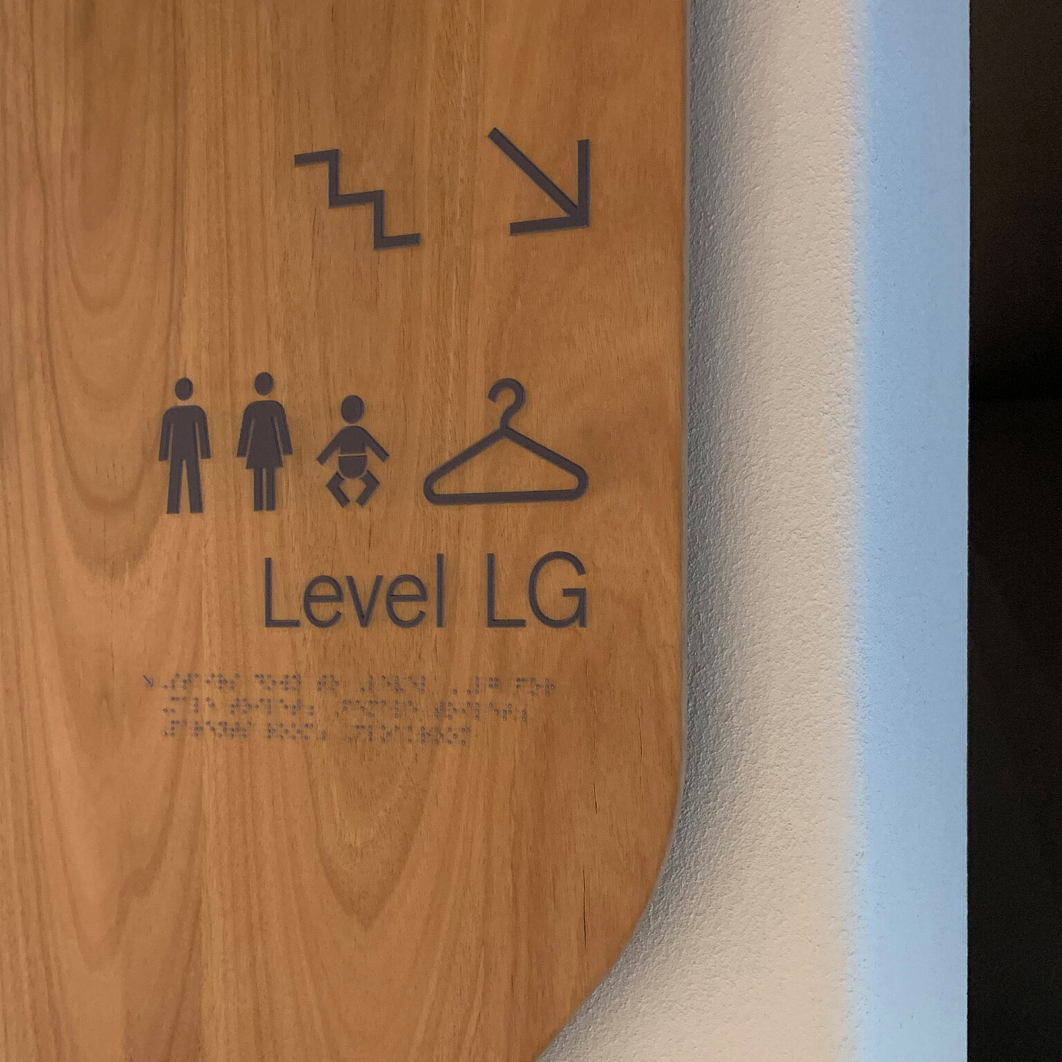 Wall-mounted directional sign detail showing tactile signage and braille