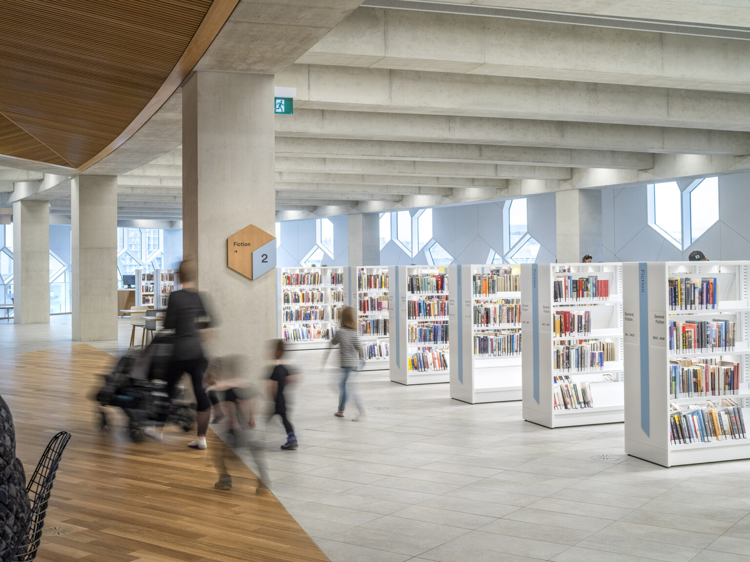 Calgary Central Library interior with column-mounted sign surrounded by book shelves and people using space