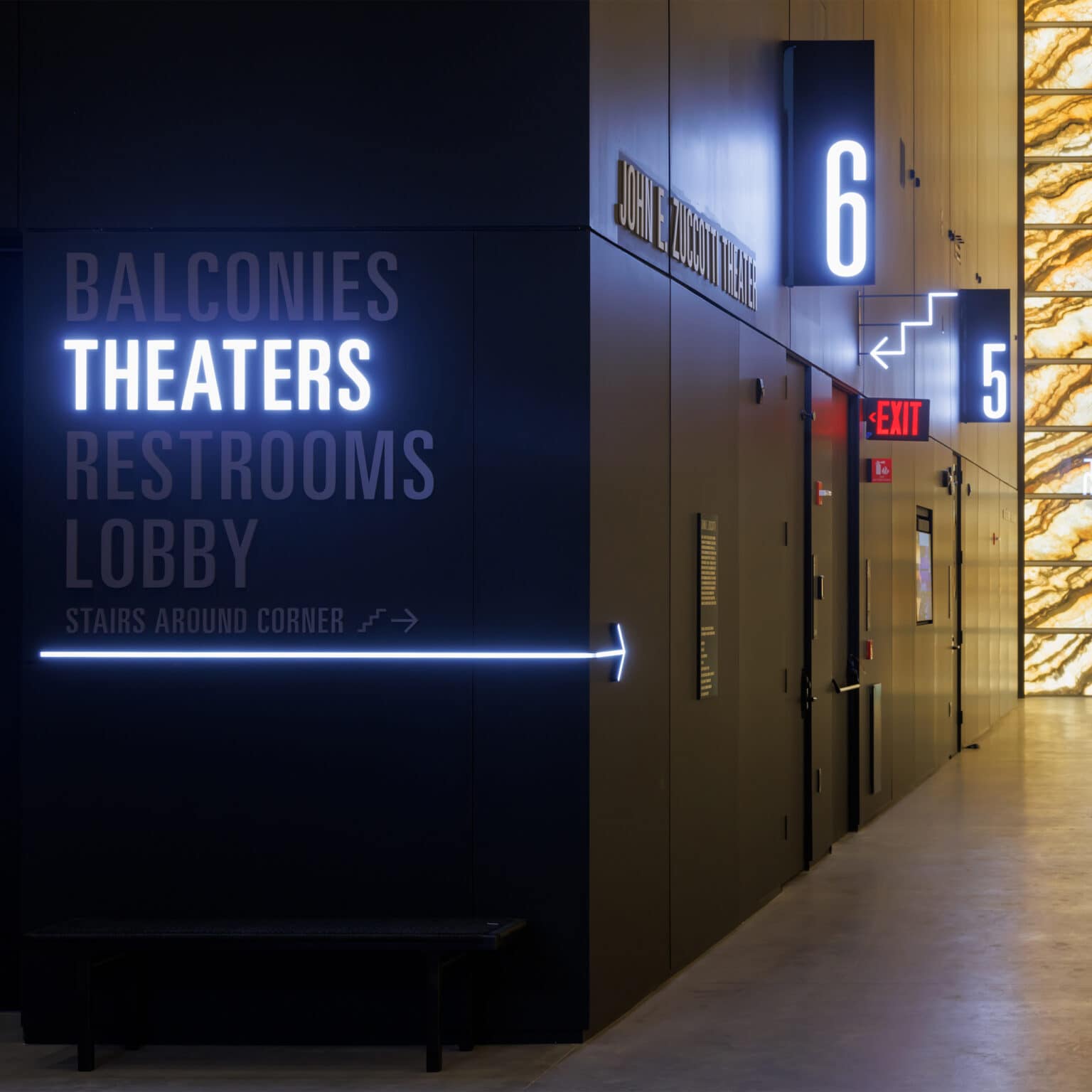 Illuminated directional signage to theatres and illuminated theatre numbers at PAC NYC. In typical theaters patrons navigate to theater names; here tickets indicate door numbers.