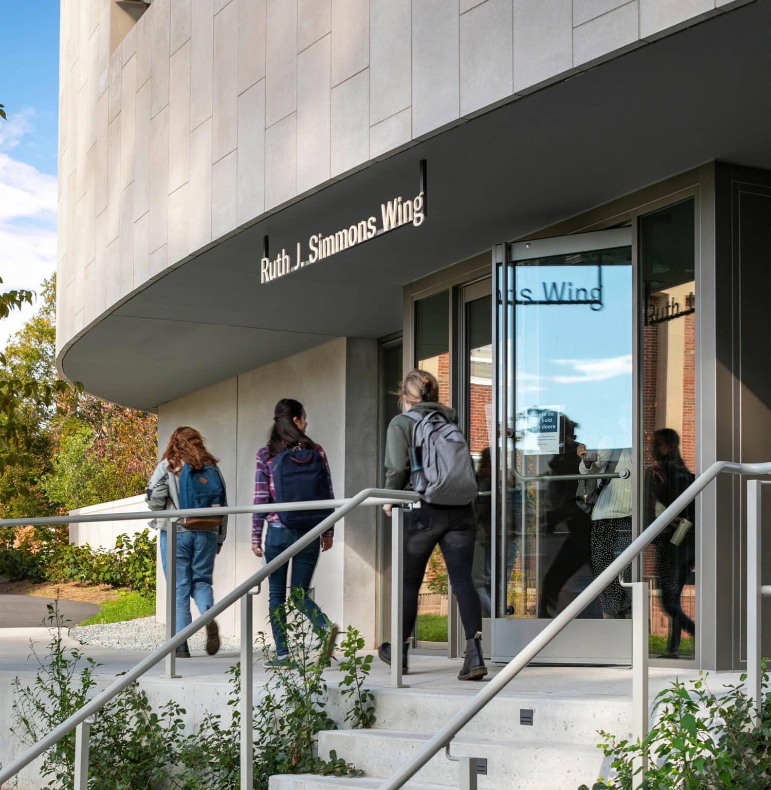 Neilson Library exterior - curved 'jewel box' with suspended indentification sign. STudents walking.