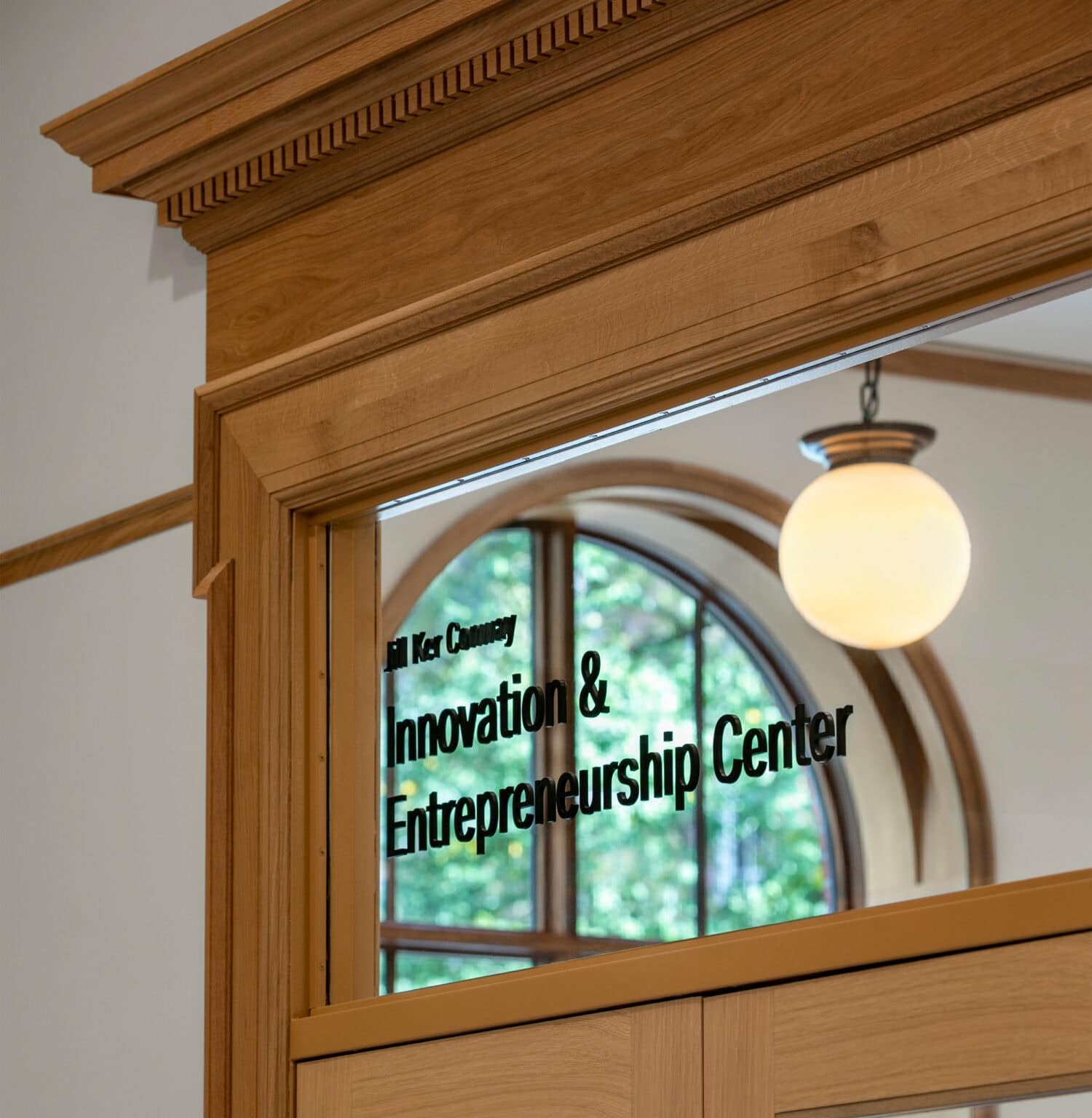 Neilson Library detail shot of Innovation & Entrepreneurship Center on glass of the top pane of a heritage door framed by wood trim