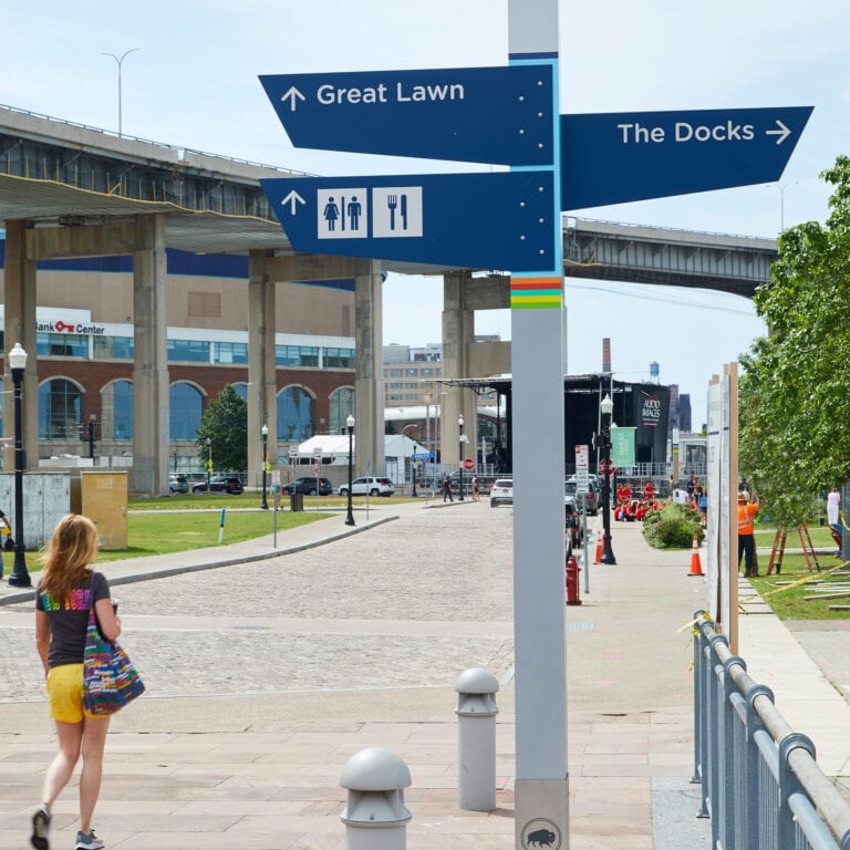 Canalside directional sign with a person walking beside it.