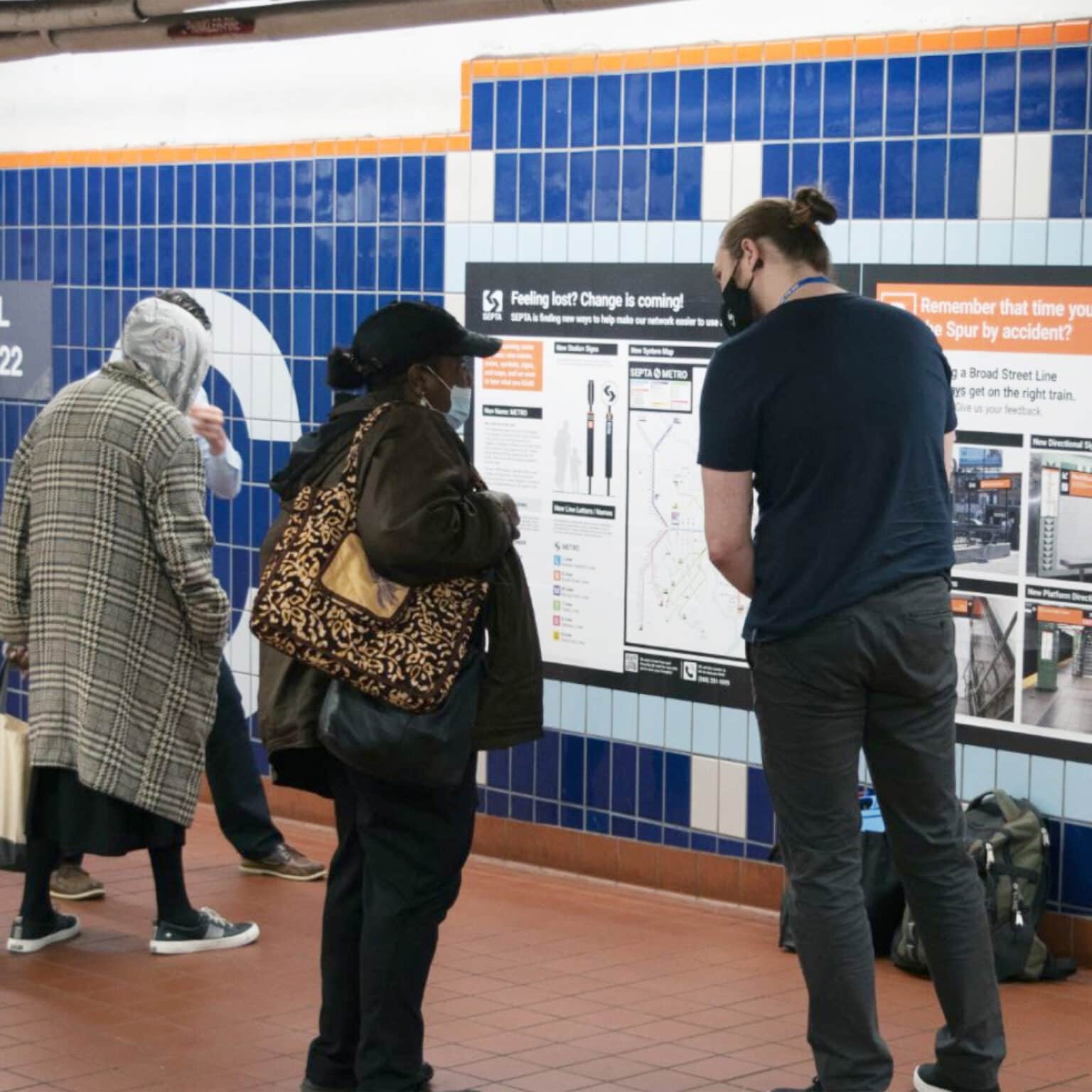 An entro researcher at a SEPTA station getting feedback on the new designs from a rider.