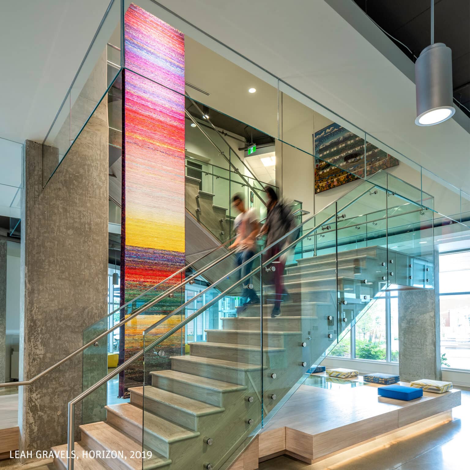Brightly coloured tapestry artwork hanging near staircase. Artist Credit: Leah Gravells, Horizon, 2019.